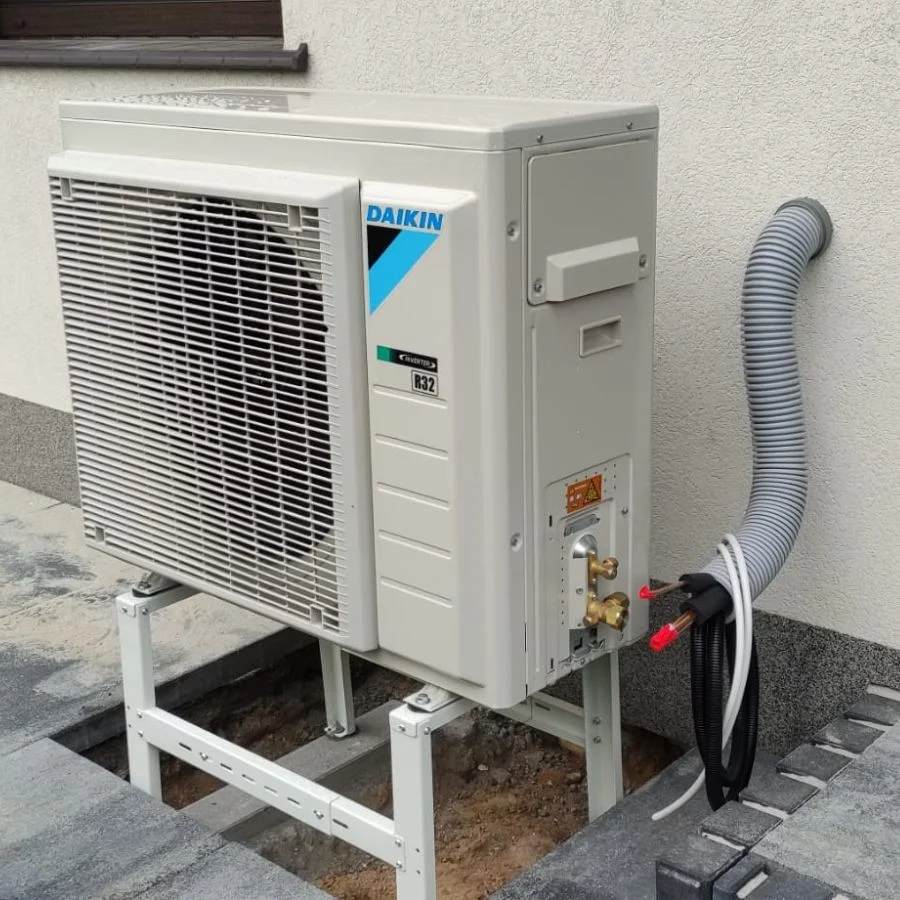 Jednostka zewnętrzna pompy ciepła Daikin na stelażu przy domu